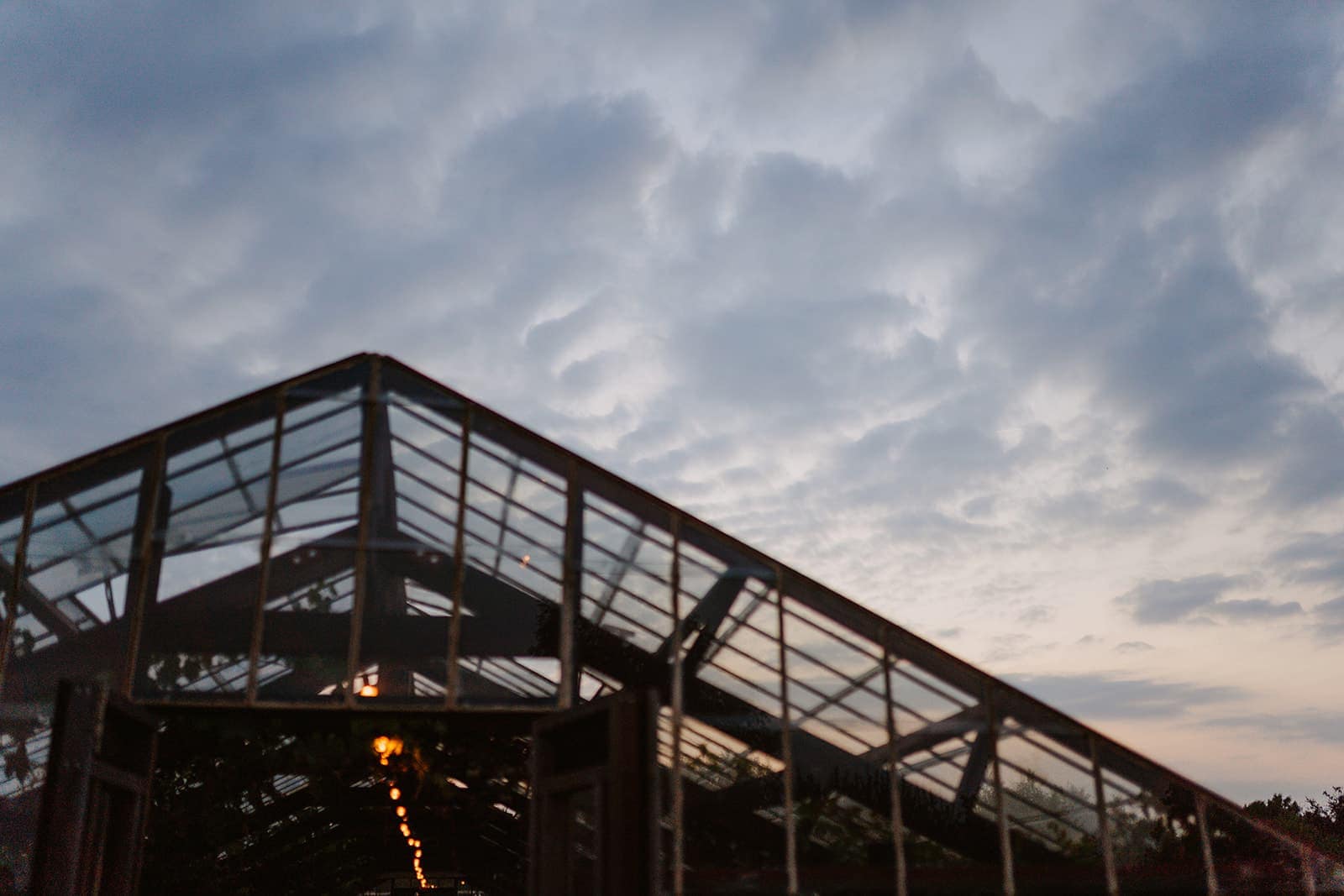 Gewächshaus bei einer Outdoor-Hochzeit in der Abendstimmung – ein besonderer Ort, der die Philosophie der Hochzeitsplanung an außergewöhnlichen Locations widerspiegelt.