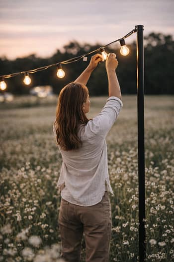 Weddingplaner mit Hands on Mentalität wechselt eine Birne in einer Lichterkette für bei einer Hochzeit