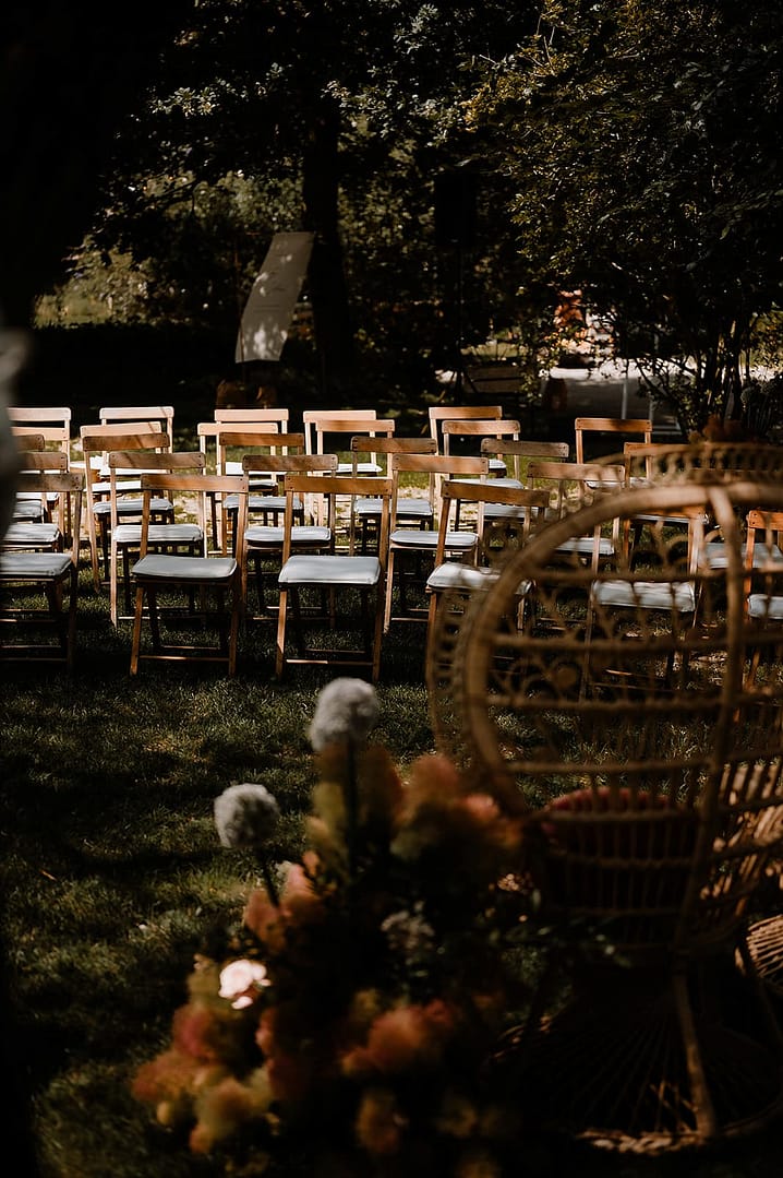 Holzstühle für eine freie Trauung im Garten eines Ferienhauses, arrangiert für eine elegante Outdoor-Hochzeit in privater Atmosphäre.
