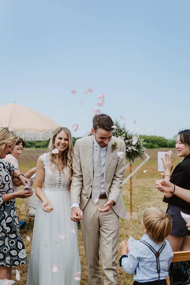 Brautpaar feiert gemeinsam mit Gästen einen emotionalen Moment im Freien