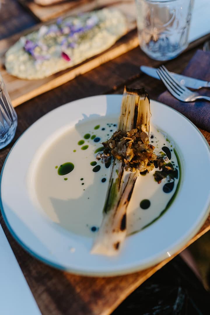 Künstlerisch angerichteter gegrillter Lauch auf einem Teller – modernes Outdoor-Dinner im Rahmen eines Events oder Hochzeitswochenendes