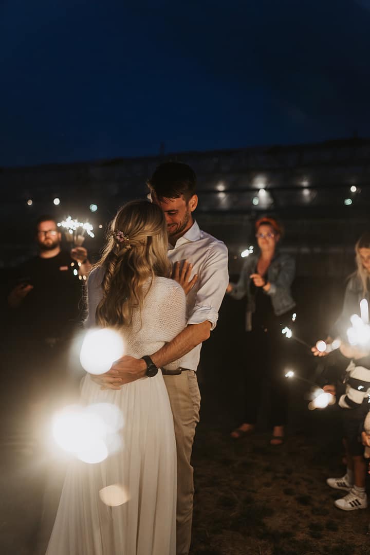 Brautpaar bei einer abendlichen Hochzeit mit Wunderkerzen – authentisch geplant von Hochzeitsplanern