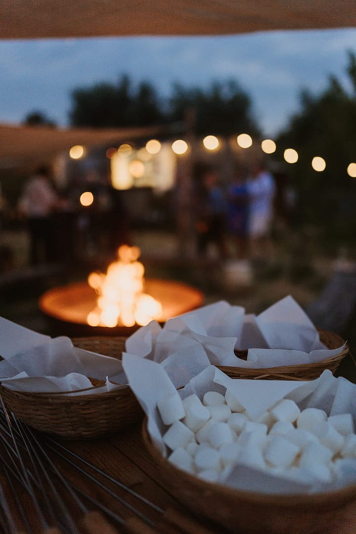 Marshmallows in Körben vor einer Feuerstelle – stimmungsvolle Abendatmosphäre bei einem Outdoor-Hochzeitsfest
