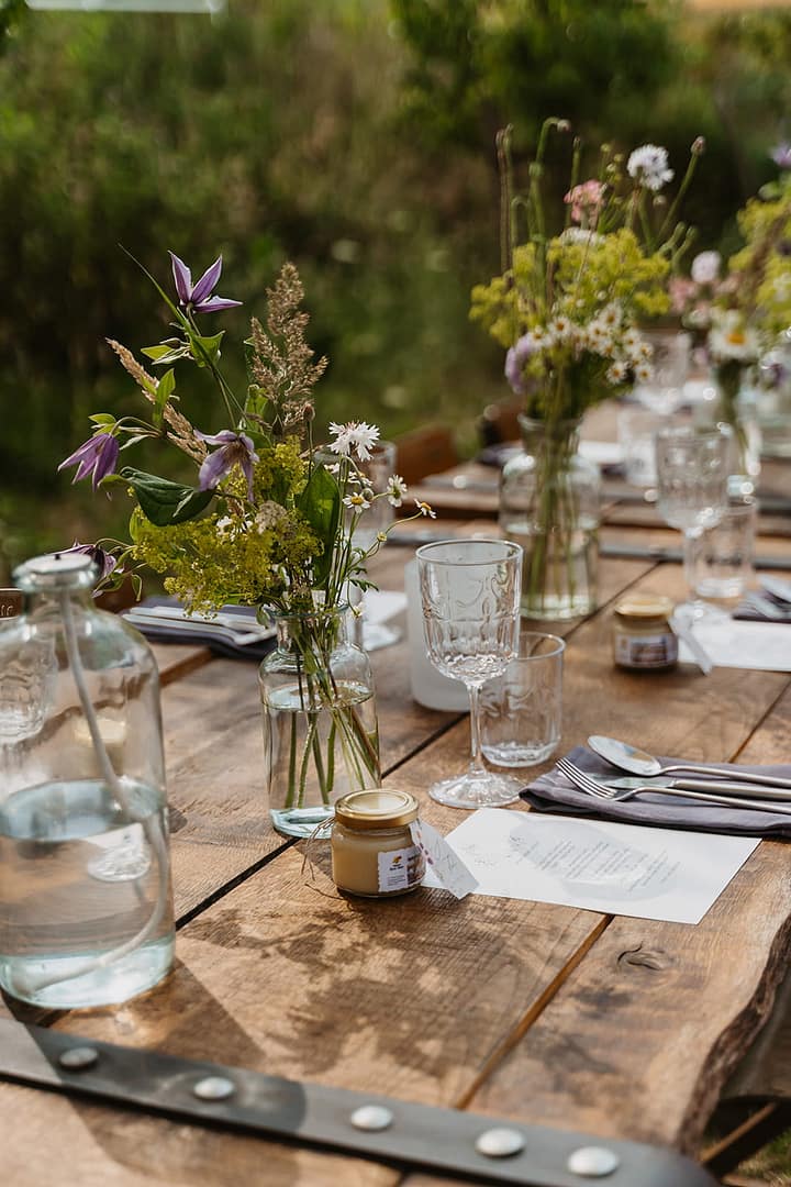 Lange Tafel mit Blumen und Kerzen bei einer naturnahen Outdoor Hochzeit