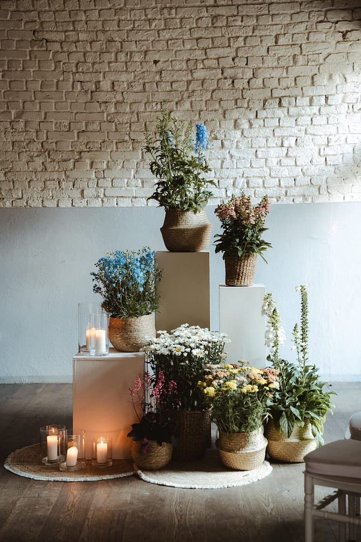 Natürliche Blumeninstallation mit Wiesenblumen, Kerzen und Leinenstoffen als Teil einer modernen Hochzeitsgestaltung