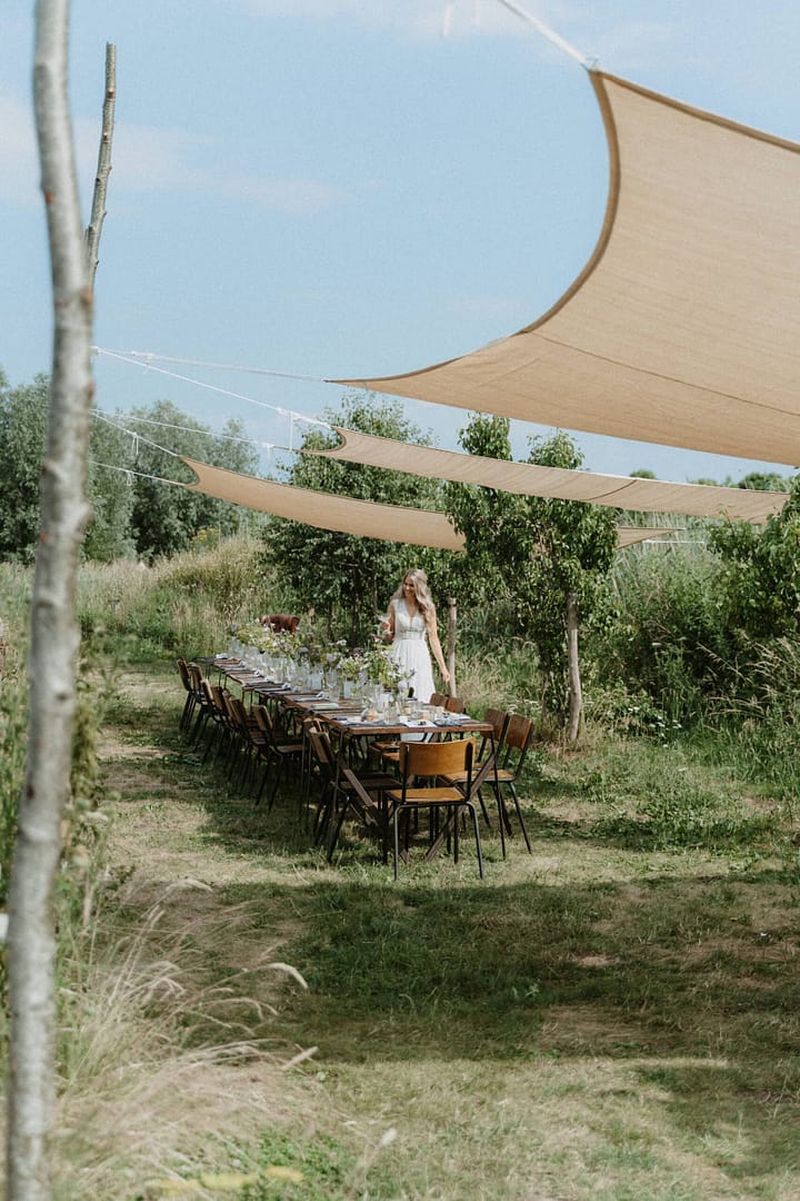 Lange Tafel unter Sonnensegeln als Teil einer stilvoll geplanten Outdoor Hochzeit