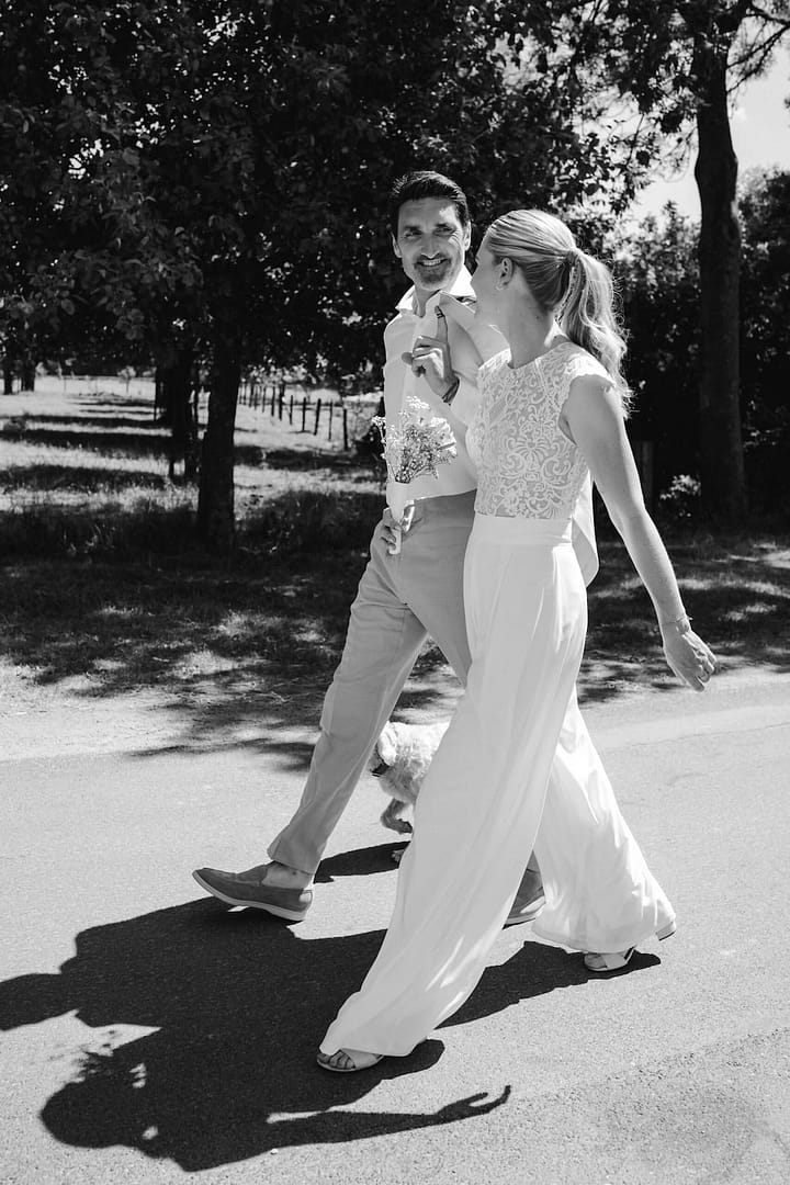 Brautpaar spaziert entspannt durch eine Allee – natürliche Outdoor Hochzeit mit persönlicher Atmosphäre