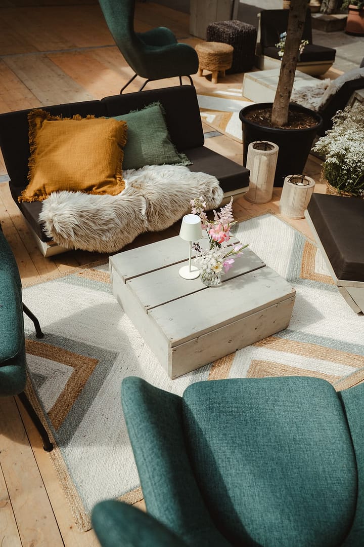Detailaufnahme einer stilvollen Lounge-Sitzecke mit Naturmaterialien und Blumenarrangements bei einer von uns gestalteten Luxury Private Estate Wedding.