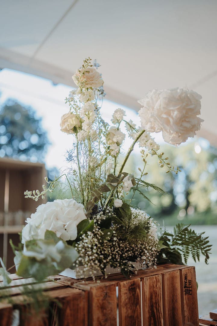 Bar-Setup in Holzoptik mit floralen Details bei einer Outdoor-Hochzeit, organisiert durch professionelle Hochzeits- und Eventplanung.