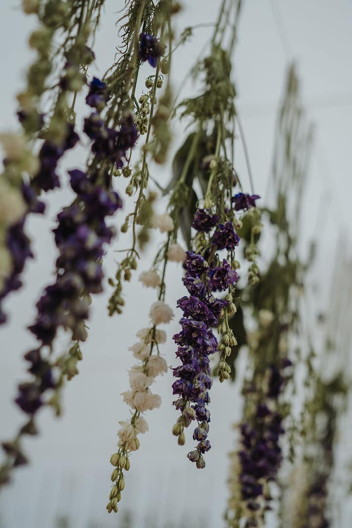 Hängende florale Installation unter einem Zelt bei einer Hochzeit im Freien auf einem weitläufigen Schlossanwesen