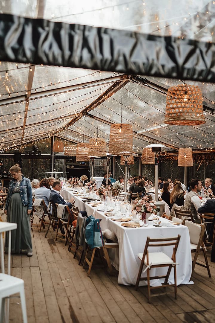 Lange festlich gedeckte Tafel unter einem Zelt bei einer Outdoor Hochzeit mit Wedding-Weekend-Charakter