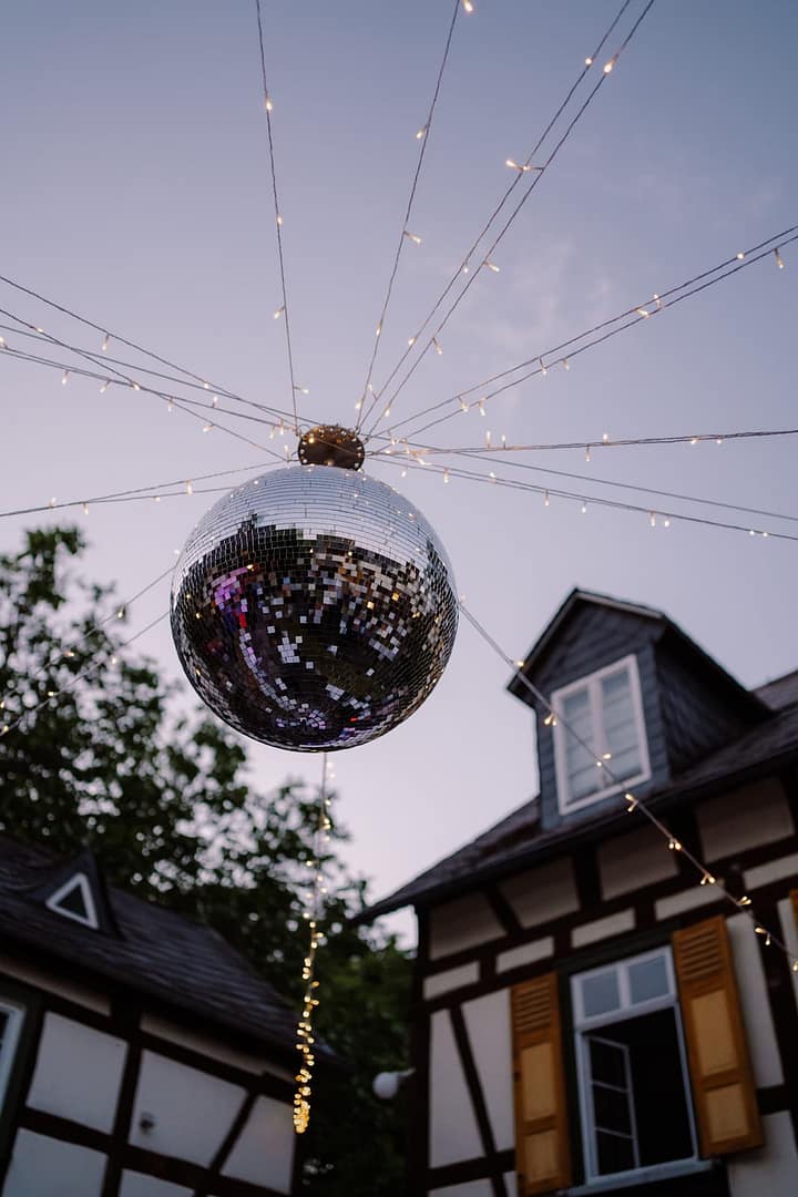 Abendstimmung bei einer Outdoor-Hochzeit mit Lichterketten und Disco-Kugel als stimmungsvolles Element des Hochzeitsabends.