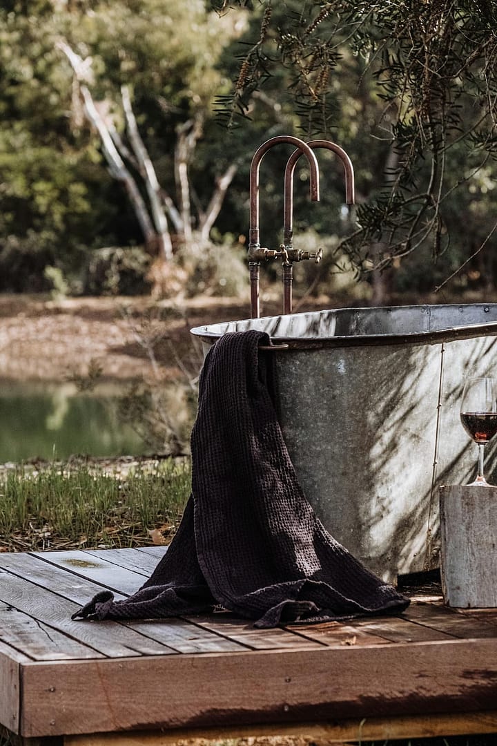 Ruhiges Outdoor-Naturdetail mit freistehender Badewanne am Wasser, inszeniert als atmosphärisches Element einer naturverbundenen Hochzeit an einer besonderen Off-Location.