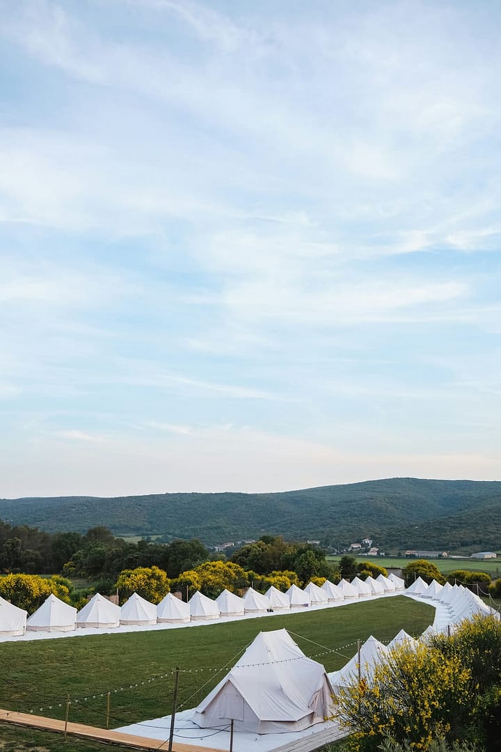 Weitläufige Zeltlandschaft auf einer offenen Wiese als Teil einer professionell geplanten Outdoor-Hochzeit an einer besonderen Off-Location.