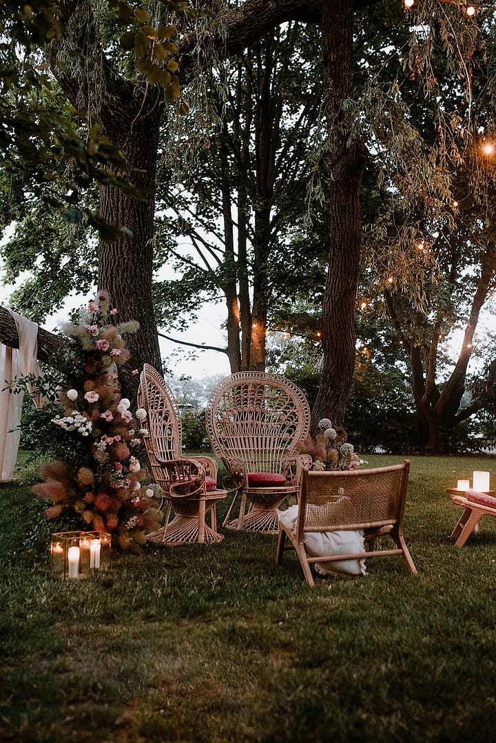 Lounge-Setting mit viel floraler Dekoration im Garten eines Ferienhauses für eine stilvolle Outdoor- und Off-Location-Hochzeit.