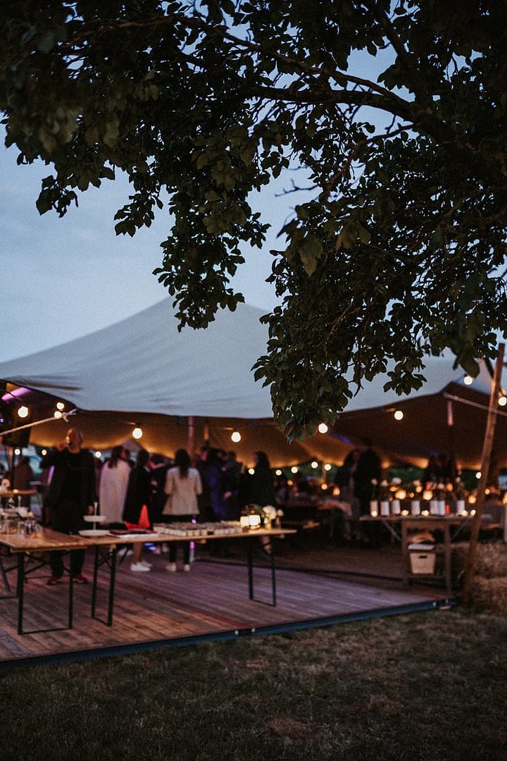 Abendliches Setting eines Wedding Weekends mit Sailcloth Zelt, Lichtern und offenen Bereichen im privaten Garten.