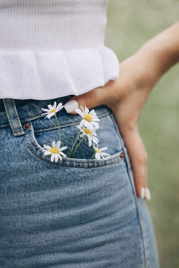 Liebe zum Detail in der Hochzeitsplanung – Gänseblümchen in der Jeans als Sinnbild für natürliche Weddingplanner Handschrift.
