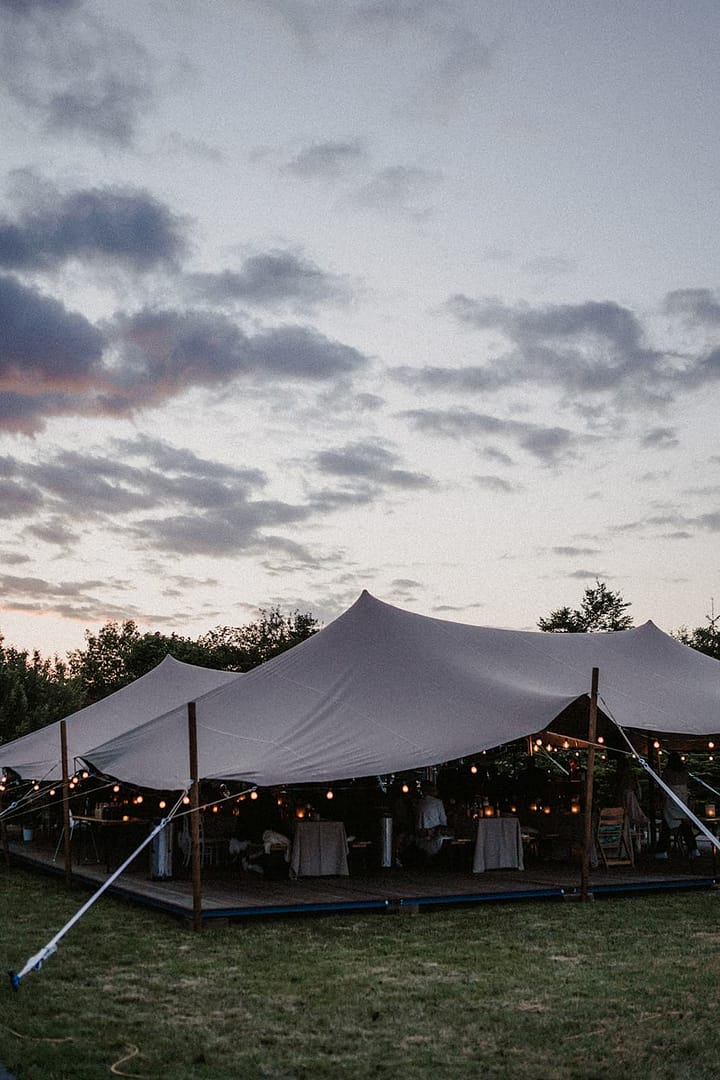 Zelthochzeit im eigenen Garten mit Lichterketten und Abendstimmung, gestaltet für ein privates Wedding Weekend.