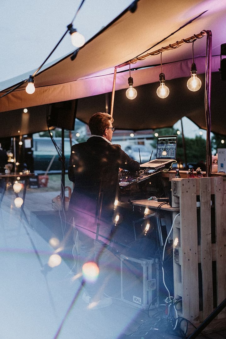 DJ und Tanzfläche unter dem Zelt bei einer Gartenhochzeit zu Hause mit ausgelassener Abendstimmung im Lichterketten Meer.