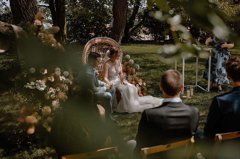 Brautpaar bei der freien Trauung im Garten eines Ferienhauses, eingebettet in ein hochwertig geplantes Outdoor-Hochzeitskonzept.