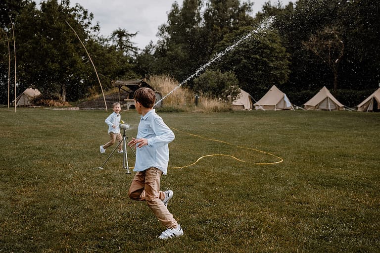 Kinder spielen auf der Wiese eines Airbnb-Ferienhauses während eines Wedding Weekends mit Glamping Zelten und Outdoor-Hochzeitsatmosphäre mit Camp Feeling.