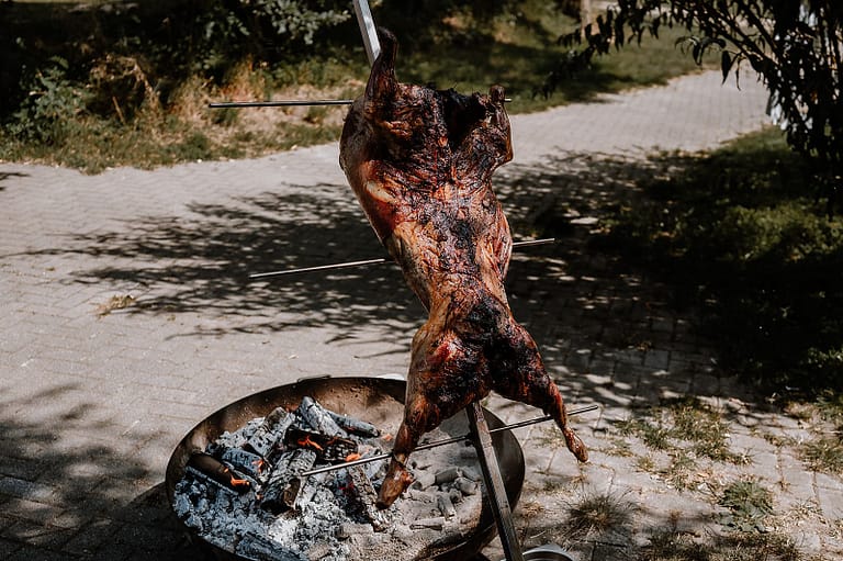Live Cooking und Open Fire Asado Outdoor Catering über offenem Feuer bei einem Wedding Weekend an einem Ferienhaus mit entspannter Off-Location-Atmosphäre.