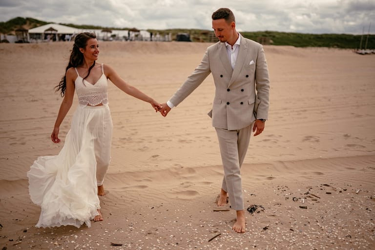 Brautpaar läuft barfuß am Strand bei einer Hochzeit in Holland