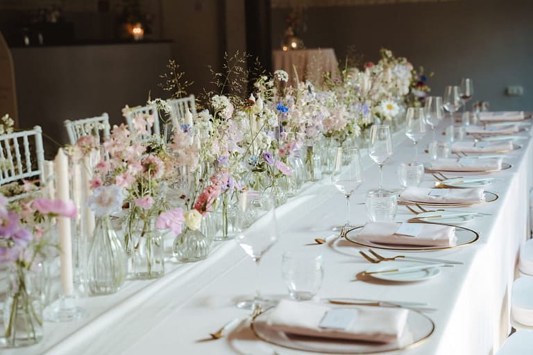 Lange Hochzeitstafel mit feiner Blumendekoration und klarer, natürlicher Gestaltung