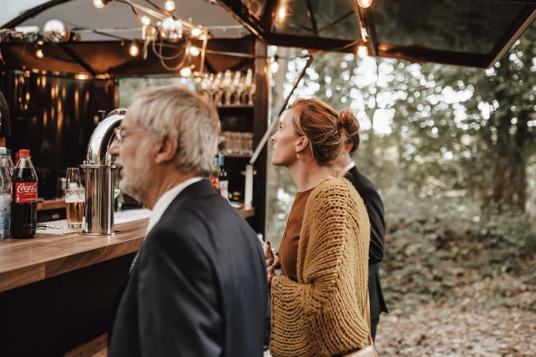 Gäste an einer mobilen Bar bzw. einem Foodtruck bei einem Outdoor Get-together auf privatem Grundstück während einer Hochzeit im Grünen