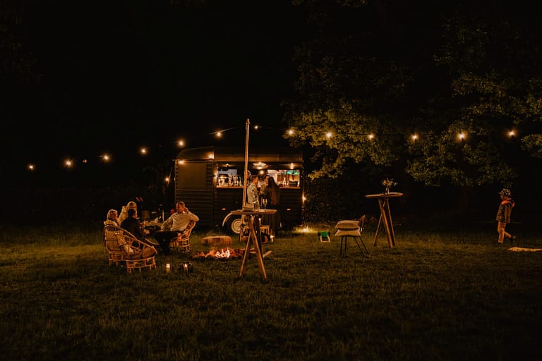 Lounge- und Barbereich mit Lichterketten und Campfire als Treffpunkt am Abend eines Hochzeitswochenendes.