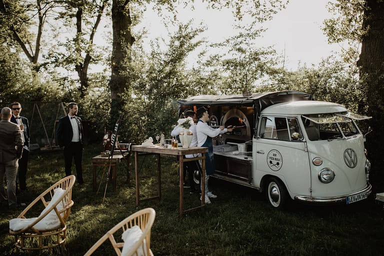 Foodtruck und Pizza Bulli im Grünen als zentraler Treffpunkt bei einer entspannten Outdoor-Hochzeit.