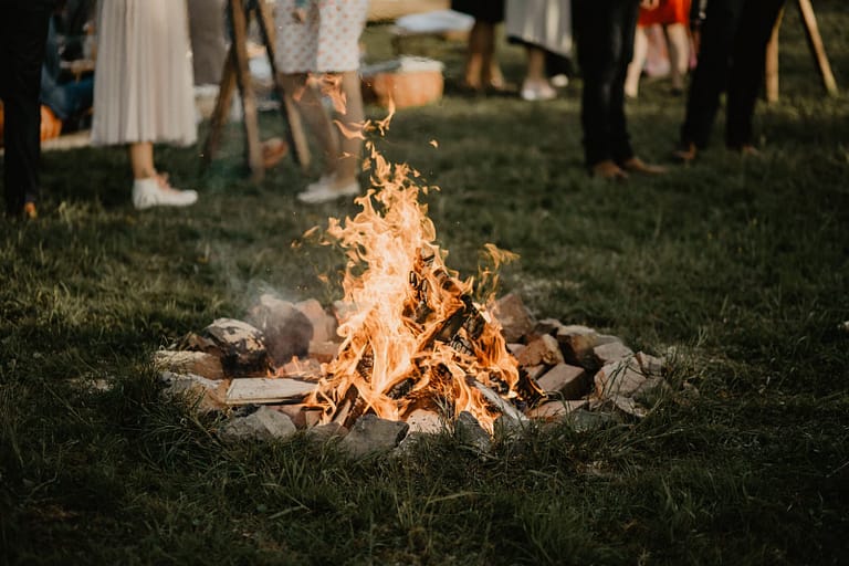 Lagerfeuer als Treffpunkt für Gäste während einer entspannten Gartenhochzeit.