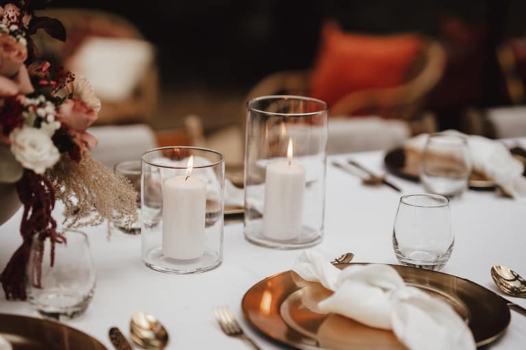 Liebevoll gedeckter Tisch mit Kerzen und Floristik für ein Outdoor Dinner im Rahmen einer Zelt- oder Gartenhochzeit