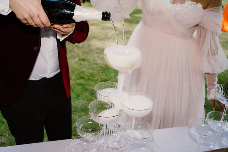 Champagner-Turm als stilvolles Highlight bei einer Outdoor-Hochzeit auf der Wiese, begleitet von natürlicher Leichtigkeit und festlicher Stimmung.