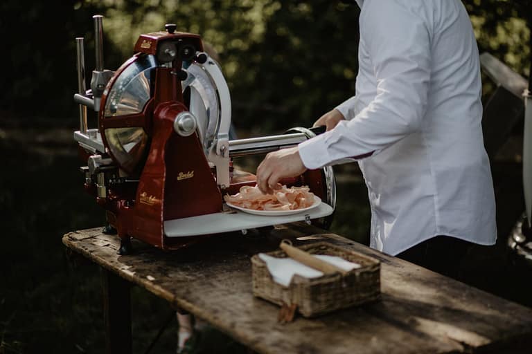 Live-Cooking-Station mit frischem Aufschnitt als Teil des kulinarischen Konzepts einer Outdoor-Hochzeit.