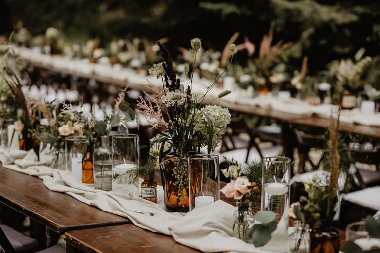 Detail einer liebevoll gedeckten langen Tafel für ein Outdoor-Dinner mitten in der Natur.