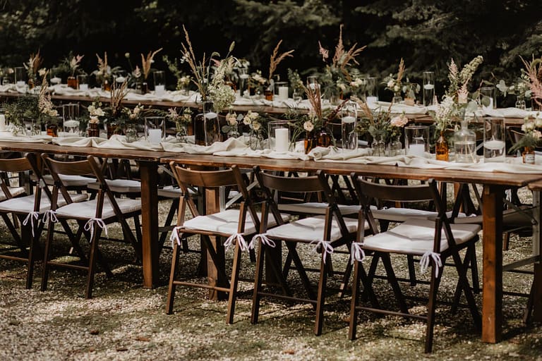 Lange Tafel für eine Outdoor-Hochzeit im Wald, eingebettet in eine natürliche Umgebung.
