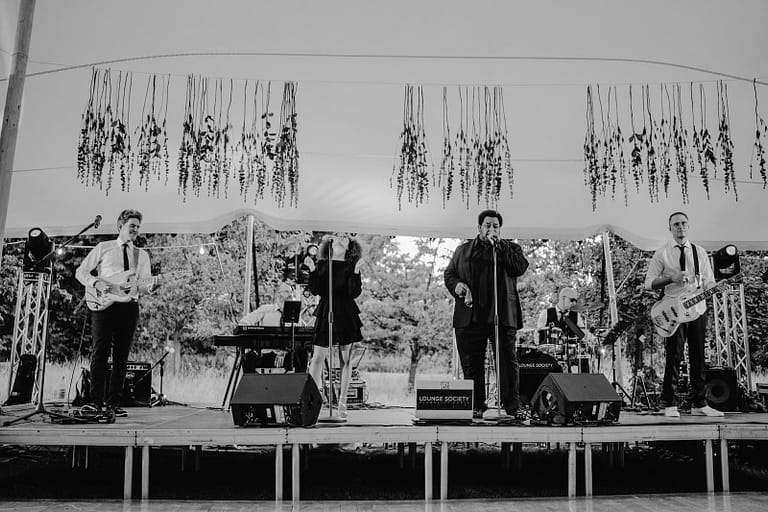 Liveband bei einer Hochzeit unter freiem Himmel in Schwarzweiß, Teil einer professionell geplanten Hochzeitsfeier.