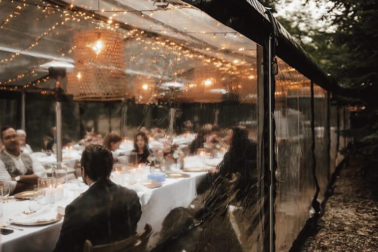 Abendliches Dinner in einer transparenten Zeltlocation mitten im Wald – Outdoor Hochzeit mit stimmungsvoller Beleuchtung
