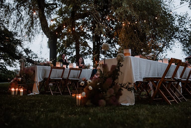 Abendliche Stimmung mit Lichterketten und langer Tafel bei einer Outdoor-Hochzeit an einem Airbnb-Ferienhaus.