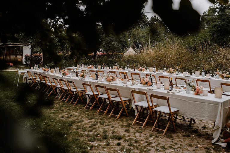 Lange Tafel für das Hochzeitsdinner im Garten eines Ferienhauses, gestaltet für eine hochwertige Outdoor-Hochzeit.