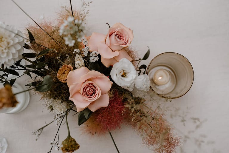 Detailaufnahme der inhouse umgesetzten Tischdekoration mit Wildflower Floristik, Verleihdekoration aus dem Hey Happy day Fundus und Kerzen bei einer Outdoor-Hochzeit an einem privaten Ferienhaus.