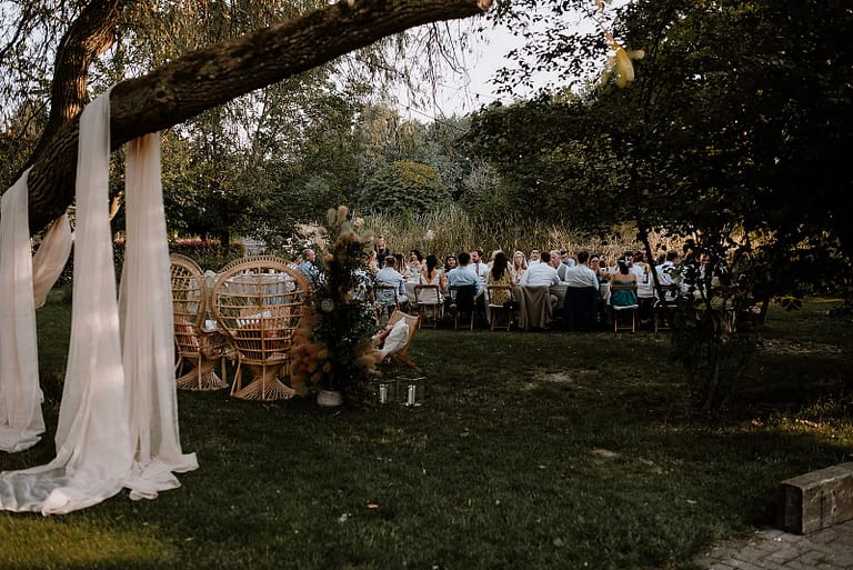 Gemeinsames Hochzeitsdinner unter Bäumen im Garten eines Airbnb-Ferienhauses als Teil eines entspannten Wedding Weekends.