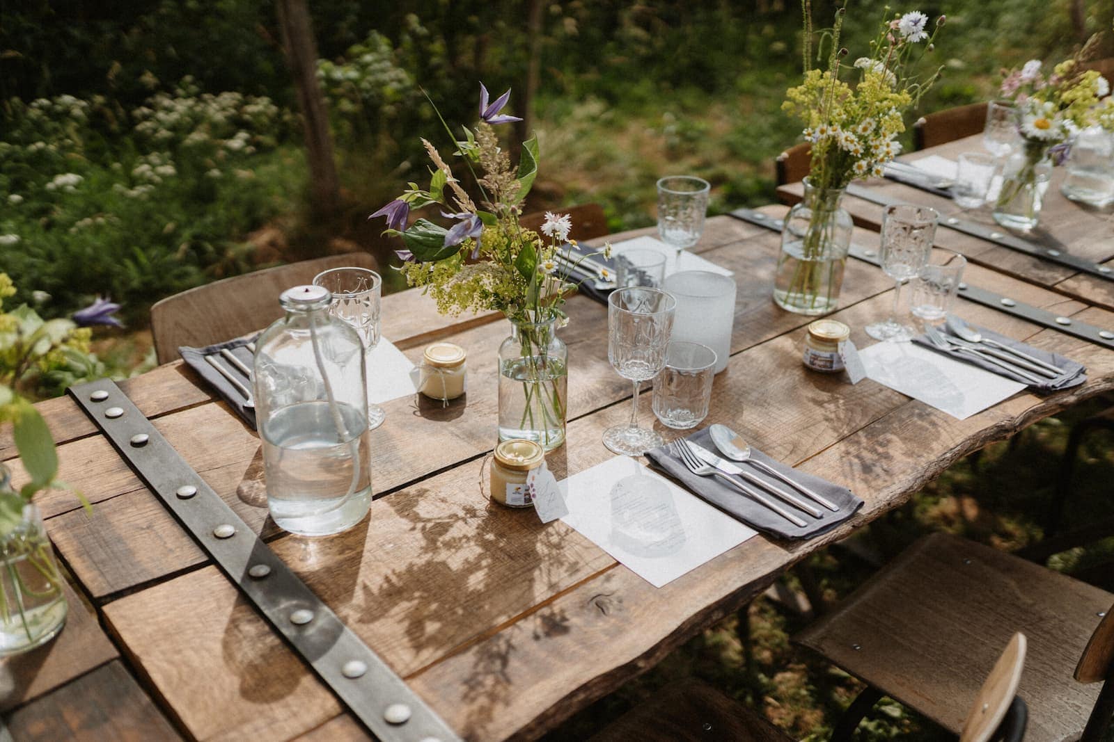 Gedeckte Holztafel mit Blumen, Gläsern und natürlicher Tischdekoration