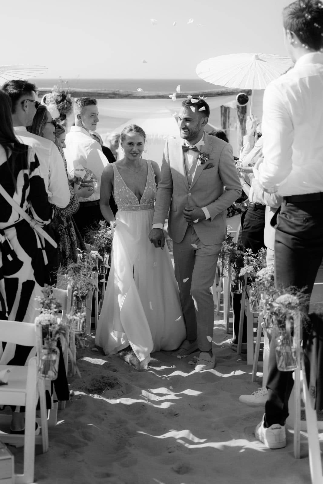 Auszug des Brautpaares bei einer Hochzeit in Holland am Strand mit Gästen und Konfetti