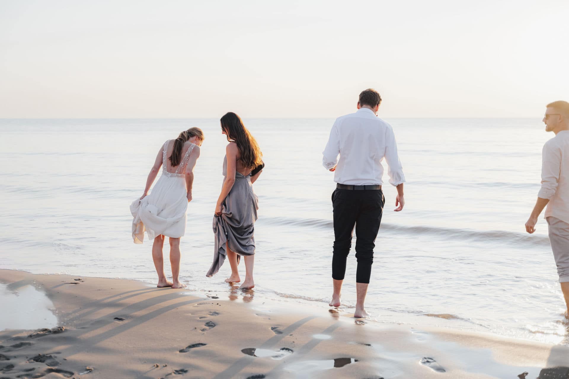 Gäste bei einer Hochzeit in Holland barfuß am Strand in entspannter Abendstimmung