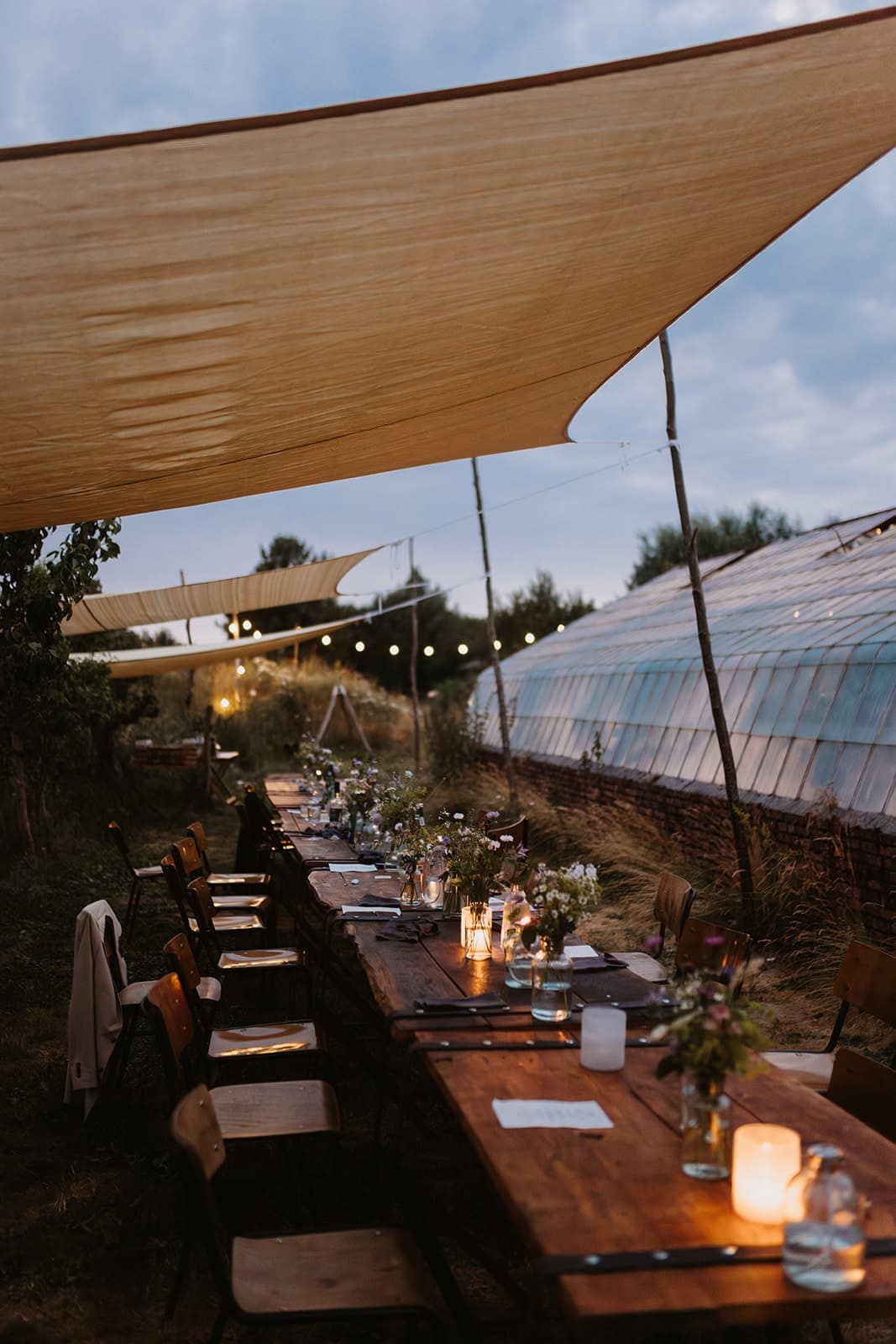 Lange Tafel am Abend mit Kerzenlicht und Sonnensegeln